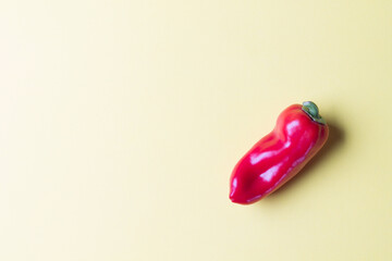 Onne ripe red bell pepper on a bright yellow background. Copy space. Concept healty eating.