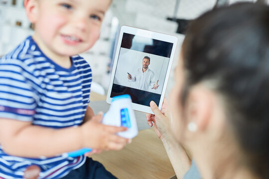 Mutter mit Kind im Videochat mit einem Kinderarzt