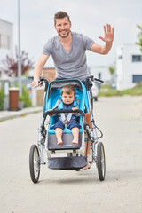 Winkender Vater transportiert sein Kind in der Stadt
