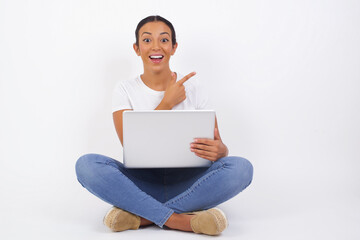 Look over there! Beautiful blonde caucasian woman pointing away and smiling to you while standing against grey background.