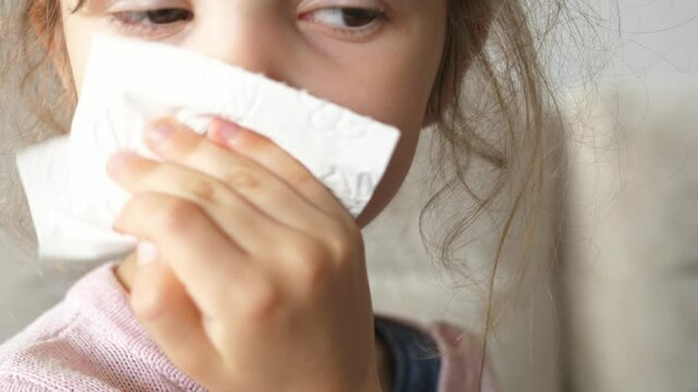 child girl with runny nose wiping nose with tissue