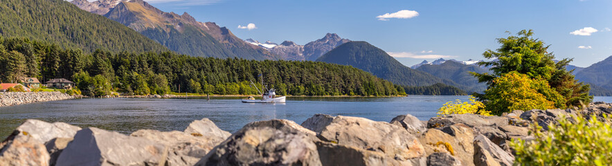 Beautiful panoramic shot of a harbour in Sitka, AK. Commercial fishing boat anchored in it, green...