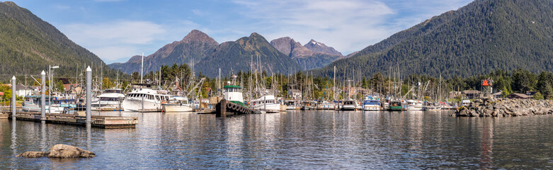 A beautiful panoramic shot of a marina in Sitka, AK with fishing boats, tugboats, yachts docked in...