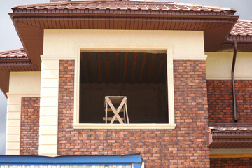   An empty window opening with a stepladder in the room of a new house under construction.