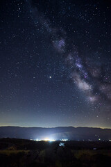 View of the Milky Way over the lights of a mountain village
