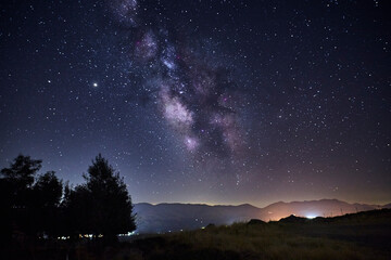 Fototapeta na wymiar View of the Milky Way over the lights of a mountain village