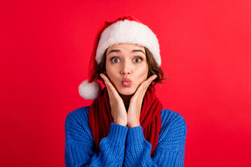 Portrait amazed funny cute girl in santa claus headwear impressed christmas magic discounts touch hands face cheeks cheekbones wear blue sweater isolated red bright color background