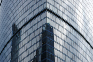 Fototapeta na wymiar Sharp corner of a modern glass skyscraper with reflections of other high-rise buildings.