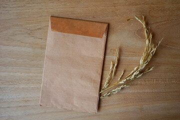Brown envelope with dried grass for greeting mockup seasonal concepts on wooden background
