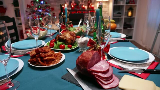 Christmas table setting with traditional food. Winter holidays. Xmas celebration in decorated room full of globe decorations and christmas tree with fireplace, big festive dinner meal for large family