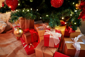 Fototapeta na wymiar holidays, new year and celebration concept - gift boxes under decorated christmas tree at home