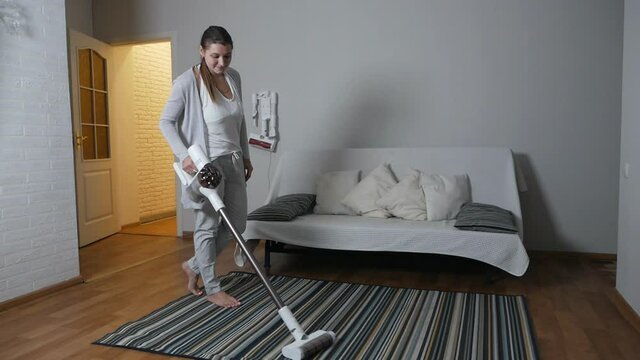 The woman cleans up with a modern vacuum cleaner, the carpet in her quart
