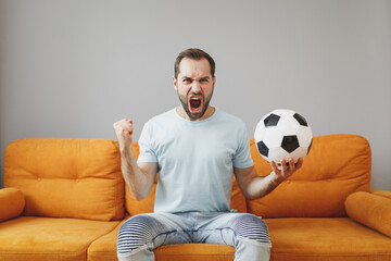 Screaming crazy young bearded man football fan 20s in basic blue t-shirt cheer up support favorite...