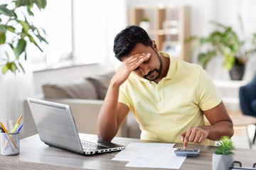 remote job, technology and people concept - stressed young indian man with calculator and papers...