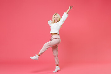 Fototapeta na wymiar Full length portrait of cheerful laughing excited young blonde woman 20s wearing white casual clothes rising spreading hands and legs looking camera isolated on bright pink colour background studio.