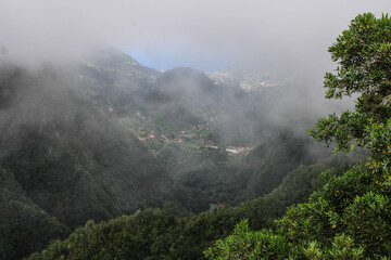Grandes montañas de arboles y plantas verdes entre nubes blancas 