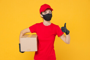 Delivery employee woman in red cap blank t-shirt uniform protect face mask gloves work courier in service during quarantine coronavirus covid-19 virus hold cardboard box isolated on yellow background.