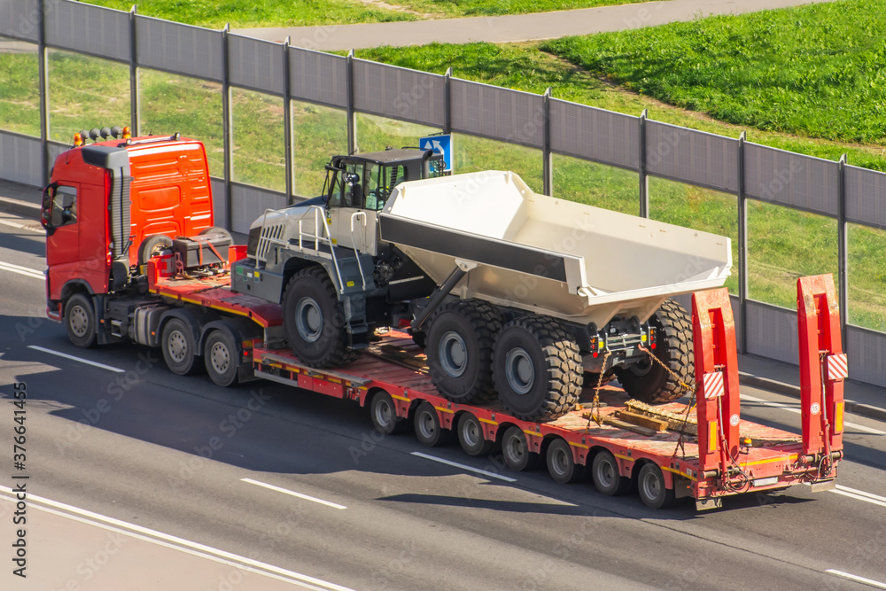 Wall mural Transportation of a huge truck for mining on the trailer platform.