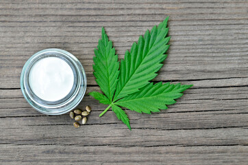 Cannabis cream in a jar with marijuana leaf and seeds on wooden background.CBD cosmetics,hemp extract,
herbal organic medicine, alternative or naturopathy concept.Selective focus.