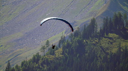 a paraglider in the air in the mountains
