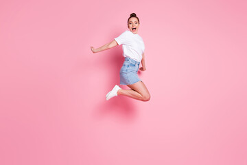Fototapeta na wymiar Full length profile photo of funky crazy lady pretty bun celebrate summer vacation beginning jump high up flight wear white t-shirt mini skirt footwear isolated pink color background