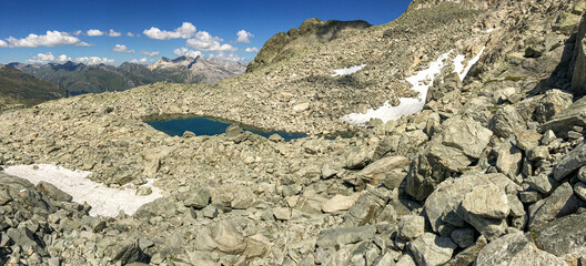 Panoramic view of an alpine lake between the rocks.