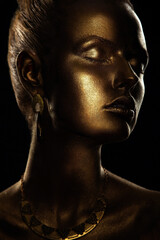 portrait of a beautiful sexy blonde girl with correct facial features artfully covered with gold paint