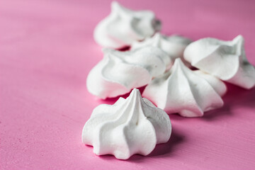 Fototapeta na wymiar White marshmallows on a pink background. Meringues lie on a bright table