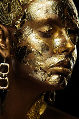 portrait of a beautiful sexy blonde girl with regular facial features artfully covered with gold...