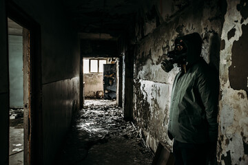 Spooky person with gas mask holding a lamp in dense fog in an abandoned building with eerie...