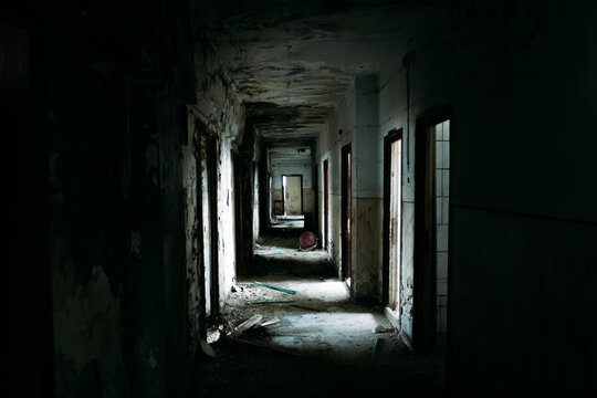 Eerie atmosphere in an abandoned building with huge windows and spider webs and one lamp. Halloween themed image. 