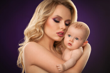 portrait of a beautiful blonde girl with skillful makeup with a baby close-up