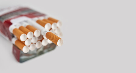 Pack full of filtered cigarettes on a gray background.