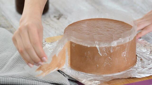 Pastry chef remove the acetate strips from chocolate mousse cake.