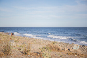 Fototapeta na wymiar people who practice bodyboard walking on a rocky beach on a wave day
