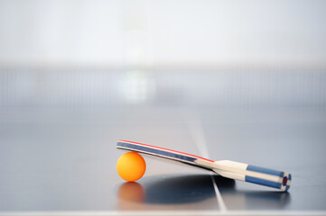 Selective focus Table tennis racket is placed over the orange ping pong ball on the table tennis...