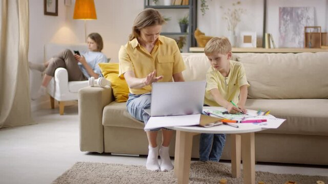 Sequence of shots of naughty little boy drawing on business document and laughing after his mother noticing it and covering her mouth in shock