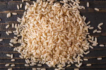 raw brown rice on dark rustic wooden background