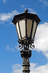 Fototapeta na wymiar Close Up of Ornate Iron Lantern on Post against Blue Sky 