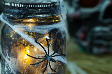 Close-up glowing jar with spider against dark background. Halloween party