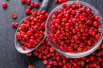 pink peppercorns on a dark stone background