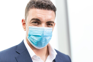 Portrait of Caucasian handsome business man wearing medical protective face mask to prevent Coronavirus or Covid19 looking at camera. concept for social distancing and new normal lifestyle. copy space