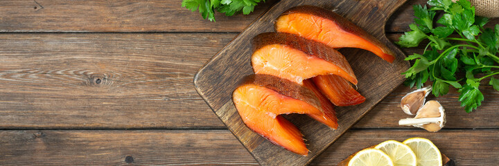 Smoked fish trout. Smoked fish steaks on a serving Board. Sliced smoked trout lay on the wooden...