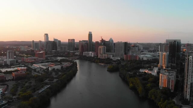 High drone shot of Downtown Austin Texas, that slowly pans toward the hills and sunset. Shot August 2020