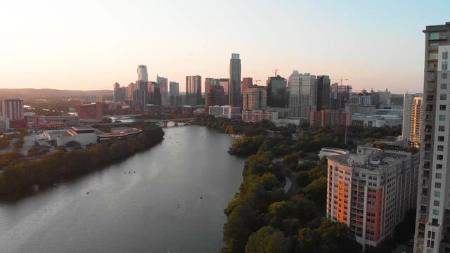 Slow rise from Rainey Street looking downtown at golden hour. Kayaks and paddle boarders can be seen on the lake.