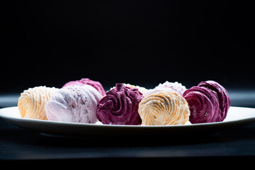 Delicious marshmallows on a plate on a dark background