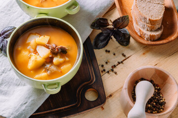  A bowl of hot thick potato soup with meat on a wooden table