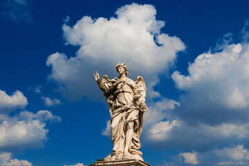 Fototapeta na wymiar Angel statue holding the Nails of Jesus Cross among clouds. A 17th century baroque masterpiece at the top of Sant'Angelo Bridge in the center of Rome