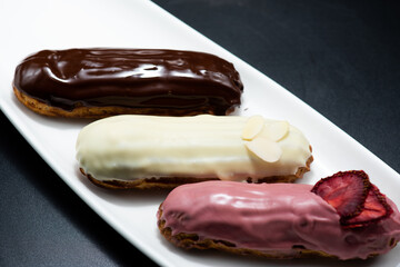 Eclairs of different flavors set on a dark background for a restaurant menu
