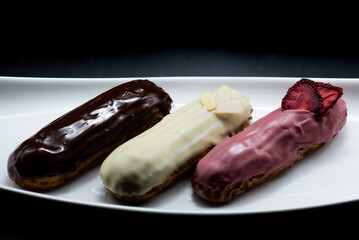 Eclairs of different flavors set on a dark background for a restaurant menu